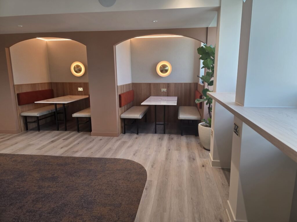 Freshly decorated office breakout area with arched booth seating and wall lights