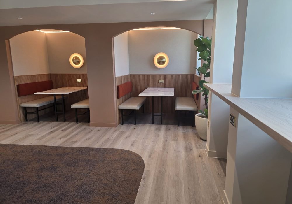Freshly decorated office breakout area with arched booth seating and wall lights